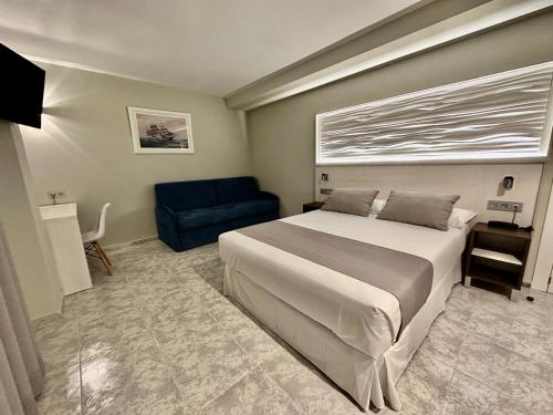 a bedroom with a large bed and a blue couch at Hotel El Paraíso in Calabardina