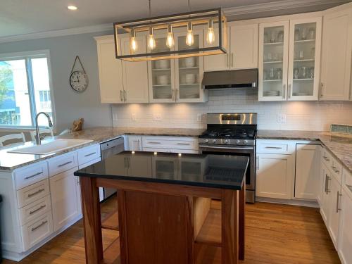 a kitchen with white cabinets and a black counter top at Tortuga home in Holden Beach