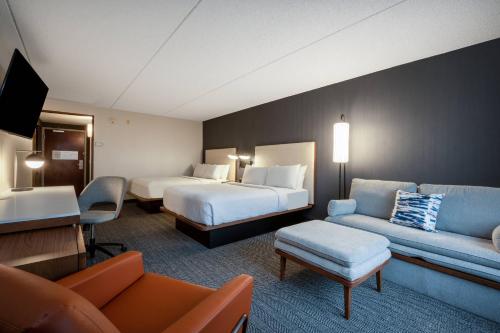 a hotel room with two beds and a couch at Courtyard Columbus Airport in Columbus