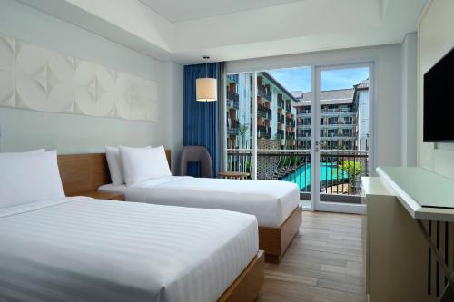 a hotel room with two beds and a balcony at Fairfield by Marriott Bali Kuta Sunset Road in Kuta