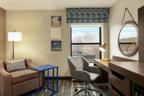 a living room with a chair and a desk and a mirror at Hampton Inn Binghamton/Johnson City in Binghamton