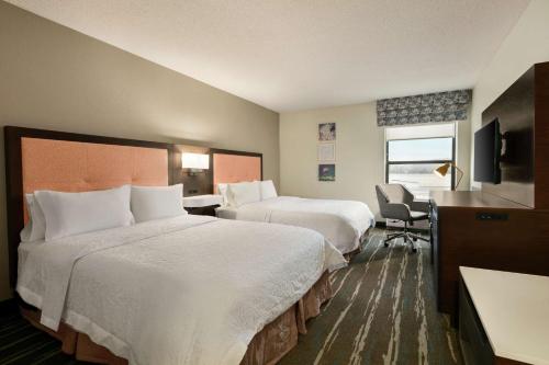 a hotel room with two beds and a desk at Hampton Inn Binghamton/Johnson City in Binghamton