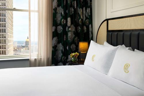 a bed with white pillows in a room with a window at The Candler Hotel Atlanta, Curio Collection by Hilton in Atlanta