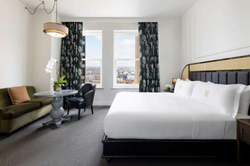 a hotel room with a bed and a couch and a window at The Candler Hotel Atlanta, Curio Collection by Hilton in Atlanta