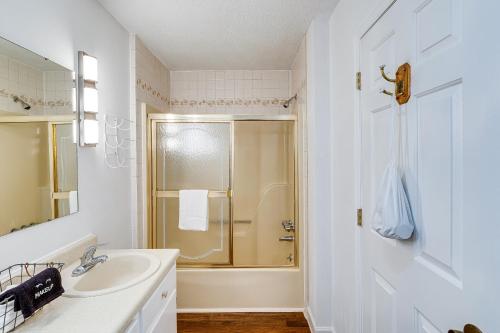 a white bathroom with a shower and a sink at Guntersville Hideaway with Mountain and Lake Views! in Albertville