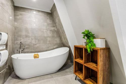 a bathroom with a white bath tub and wooden shelves at Nature's Nook with Spa, Deck and Views in Piha