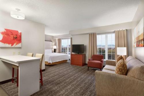 a hotel room with a bed and a couch and a television at Homewood Suites by Hilton Columbus-Dublin in Dublin
