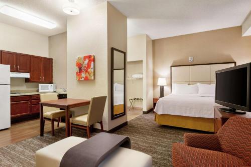 a hotel room with a bed and a kitchen at Homewood Suites by Hilton Dallas-DFW Airport N-Grapevine in Grapevine