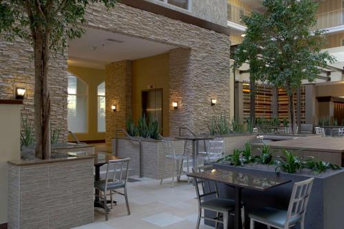 a restaurant with tables and chairs and plants at Embassy Suites by Hilton Dallas Market Center in Dallas