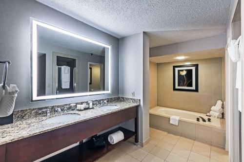a bathroom with two sinks and a bath tub at Embassy Suites by Hilton Dallas Market Center in Dallas