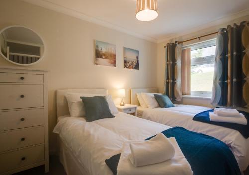 a bedroom with two beds and a window at Y Nyth in Y Felinheli