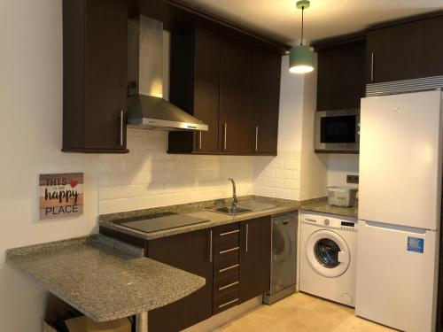 a kitchen with brown cabinets and a washer and dryer at CriteriaHome! nice&easy in Madrid