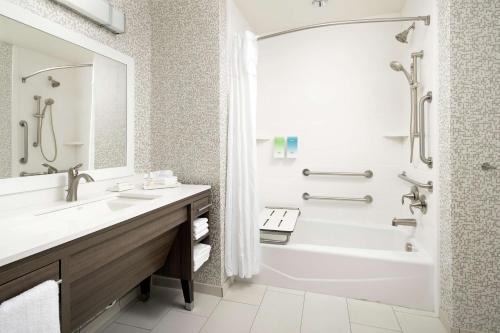 ein Badezimmer mit einer weißen Badewanne, einem Waschbecken und einem Badetubermott in der Unterkunft Home2 Suites By Hilton Longmont in Longmont