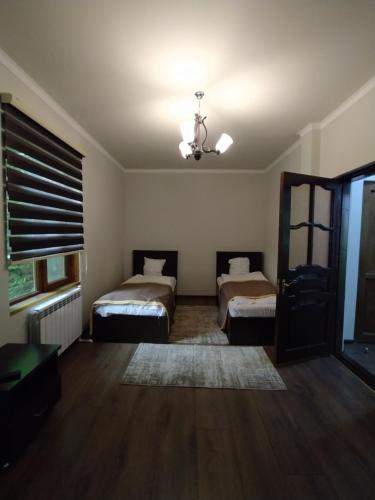 a bedroom with two beds and a window and a ceiling at Qusar Qala Hotel in Qusar