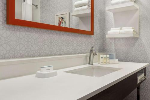 La salle de bains est pourvue d'un lavabo blanc et d'un miroir. dans l'établissement Hampton Inn Sacramento/Rancho Cordova, à Rancho Cordova