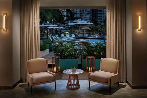 a room with two chairs and a table and a pool at The Gates Hotel South Beach in Miami Beach
