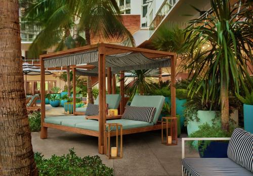 a wooden gazebo with benches and palm trees at The Gates Hotel South Beach in Miami Beach