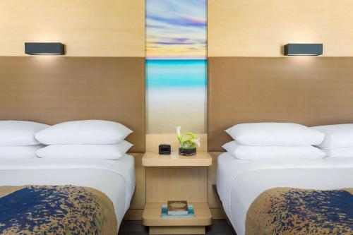 two beds in a hotel room with a window at The Gates Hotel South Beach in Miami Beach