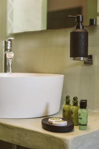 a bathroom counter with a sink and two bottles of soap at Ambeli Apartments in Perivolos