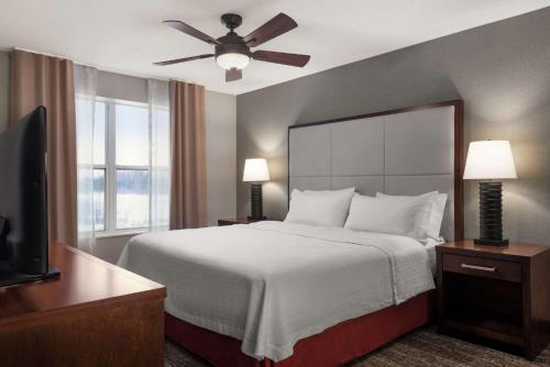 a hotel room with a bed and a ceiling fan at Homewood Suites Rochester-Henrietta in Henrietta