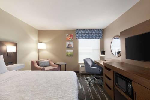 a hotel room with a bed and a flat screen tv at Hampton Inn Tracy in Tracy