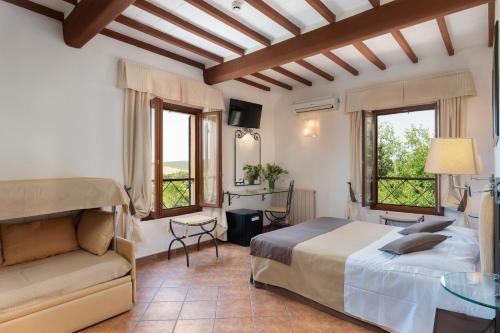 Hotel Ristorante Borgo Antico في مونتيروني دي اربيا: غرفة نوم بسرير واريكة ونوافذ