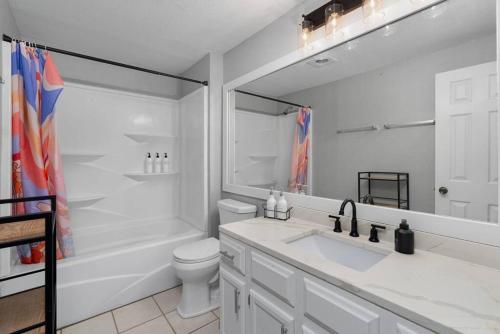 a bathroom with a sink and a toilet and a mirror at That 70s House -Fun 6 Bedroom W Pool & Game Room in Round Rock