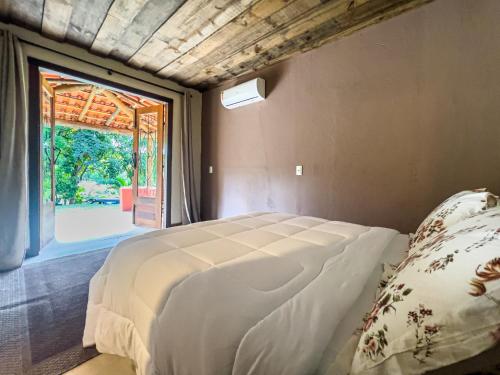 a bedroom with a bed and a large window at Hotel Fazenda Filhos do Vento in Cachoeiras de Macacu