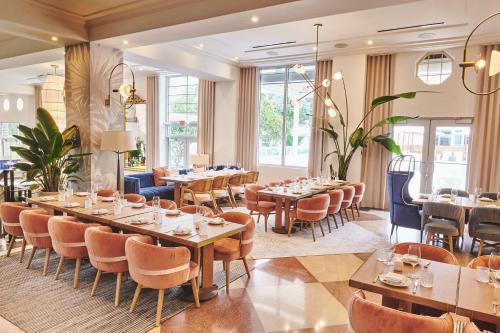 a restaurant with tables and chairs and windows at The Gabriel Miami South Beach, Curio Collection by Hilton in Miami Beach