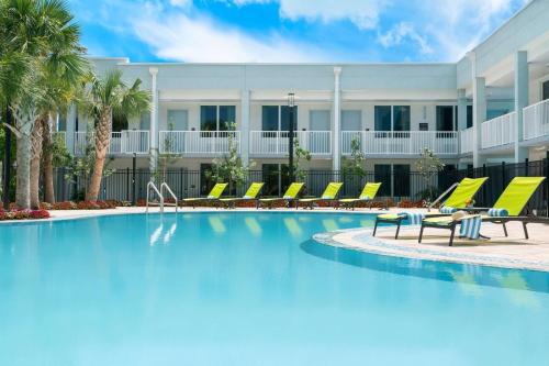 a swimming pool with yellow lounge chairs and a building at Hilton Garden Inn Key West / The Keys Collection in Key West
