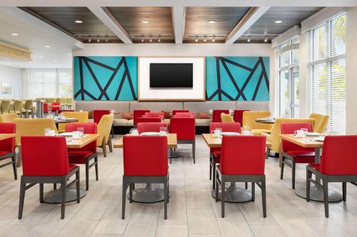 a dining room with tables and chairs and a flat screen tv at Hilton Garden Inn Key West / The Keys Collection in Key West