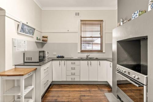 a kitchen with white cabinets and a wooden floor at Avondale 7 Cashmore Street in Evans Head