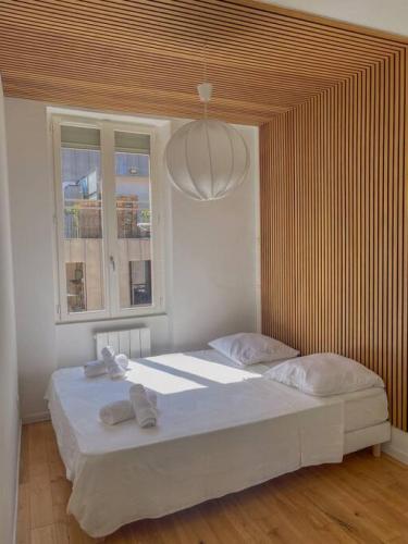 une chambre avec un grand lit blanc avec un plafond en bois dans l'établissement Superbe Appartement au bord de la Garonne Toulouse, à Toulouse