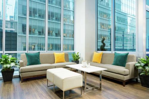 a living room with couches and a table and windows at Hilton Garden Inn New York - Times Square Central in New York