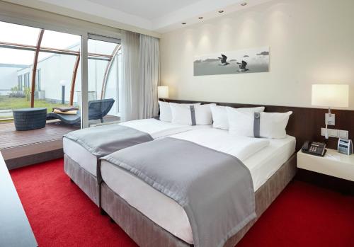 シェーネフェルトにあるホリデイ イン ベルリン エアポート - カンファレンス センターの赤いカーペットフロアの客室で、大きなベッドが備わります。