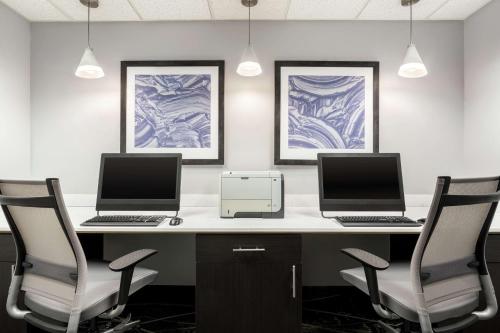 two computers sitting on a desk with two chairs at Homewood Suites by Hilton Erie in Erie