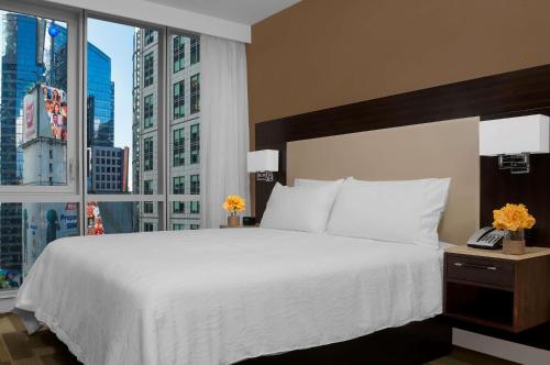 - une chambre avec un grand lit et une grande fenêtre dans l'établissement Hilton Garden Inn New York - Times Square Central, à New York