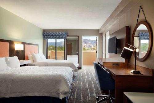 ein Hotelzimmer mit 2 Betten, einem Schreibtisch und einem Spiegel in der Unterkunft Hampton Inn Sedona in Sedona