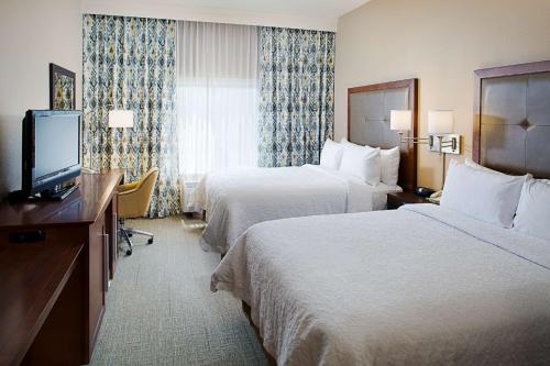 a hotel room with two beds and a flat screen tv at Hampton Inn & Suites Palmdale in Palmdale