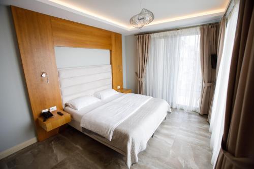 a bedroom with a white bed and a large window at Hotel GRINT in Golem