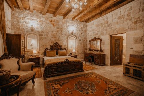a bedroom with a bed and a chair and a mirror at Serenus Cave Suites in Ortahisar