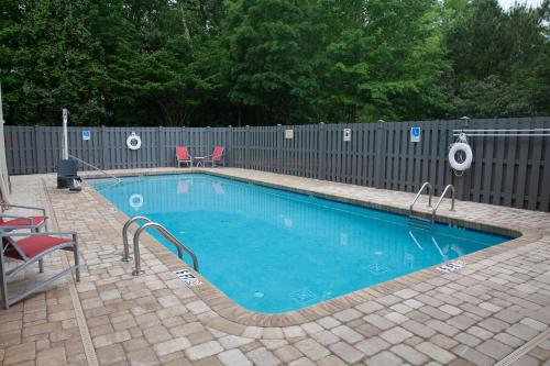a swimming pool with two chairs and a fence at DoubleTree by Hilton Atlanta Alpharetta-Windward in Alpharetta