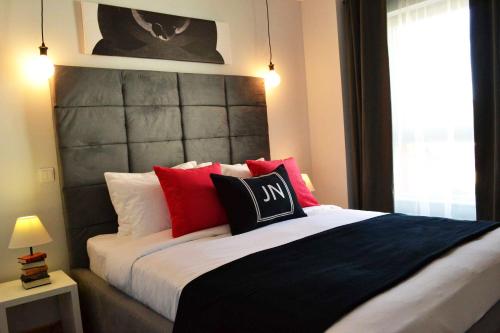 a bedroom with a large bed with red and black pillows at JN Boutique Apartments in Bucharest