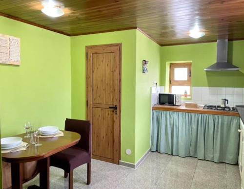 a room with a table and a kitchen with green walls at Vv Casa Maye Pepa en Teror in Teror