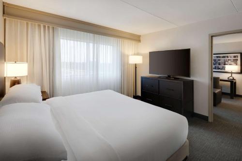 ein Hotelzimmer mit einem Bett und einem Flachbild-TV in der Unterkunft Embassy Suites by Hilton Detroit Troy Auburn Hills in Troy