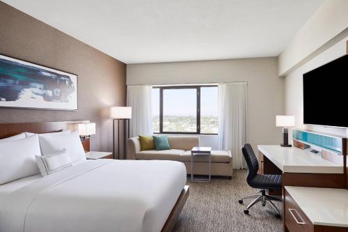 ein Hotelzimmer mit einem großen weißen Bett und einem Schreibtisch in der Unterkunft Delta Hotels by Marriott Phoenix Mesa in Mesa