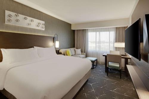 ein Hotelzimmer mit einem großen Bett und einem Schreibtisch in der Unterkunft Embassy Suites by Hilton Atlanta Perimeter Center in Atlanta