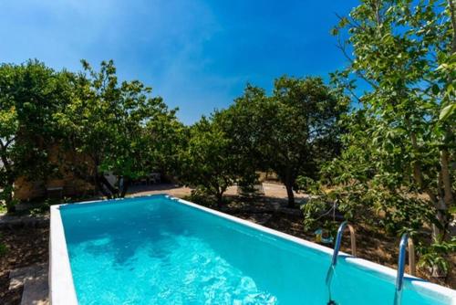 een blauw zwembad met bomen op de achtergrond bij Trullo Mareposa in Sannicola