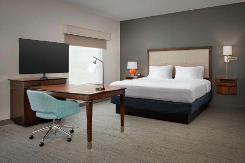 Hampton Inn & Suites Portland/Hillsboro-Evergreen Park في هيلزبورو: غرفة في الفندق بها سرير ومكتب وبه جهاز كمبيوتر