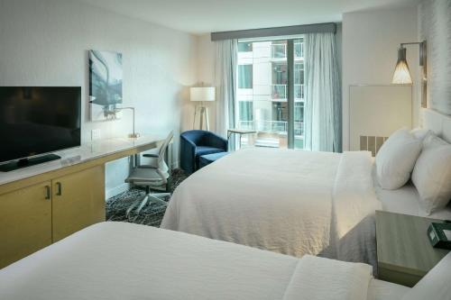 Hilton Garden Inn Seattle Bellevue Downtown, WA في بلفيو: غرفة فندقية بسريرين ومكتب وتلفزيون